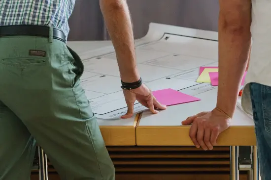 Two people standing at a table, with notes and drawings.
